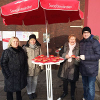 GenossInnen am Infostand mit roten Krapfen